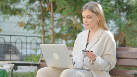 Young Business Lady Excited for Successful Online Shopping on Laptop Outdoorの写真素材