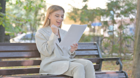 Young Business Lady Celebrating and Reading Documents Outdoorの写真素材