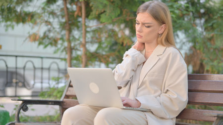 Young Business Lady with Neck Pain Working on Laptop Outdoorの写真素材