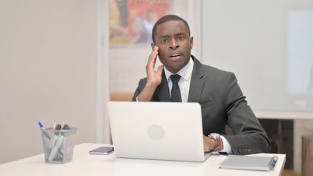 Shocked African Businessman Looking at Camera in Officeの写真素材