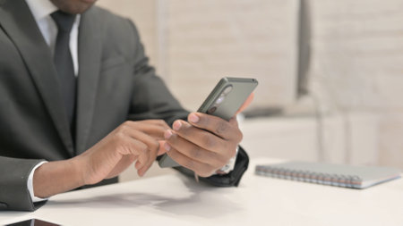 Close Up of African Businessman Using Smartphone in Officeの写真素材