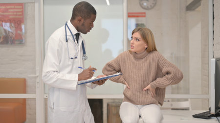 Woman with Back Pain Consulting an African Orthopedic Doctorの写真素材