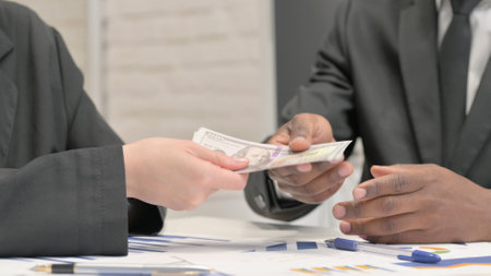 Close up of Businesswoman giving Money to African Businessmanの写真素材