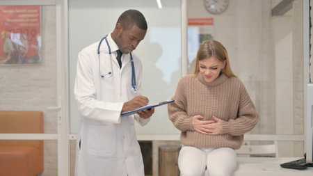 Woman with abdominal Pain Talking with African Doctor for Treatmentの写真素材
