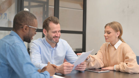 Young Entrepreneurs Discussing Paperwork in Officeの写真素材