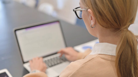 Rear View of Woman Typing on Laptopの写真素材