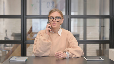 Young Woman Talking on phone in Officeの写真素材