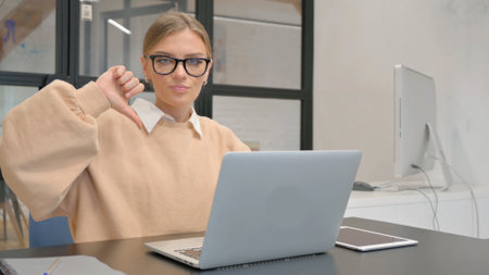 Thumbs Down by Female Worker Using Laptopの写真素材