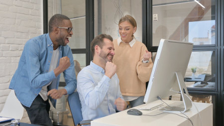 Multi Ethnic Young People Celebrating Success on Computerの写真素材