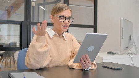 Female Worker Doing Video Chat on Tablet in Officeの写真素材