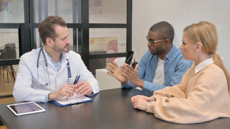 Mixed Race Couple Discussing Health Problems with Doctorの写真素材