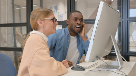 Interracial Couple Celebrating Success on Computerの写真素材