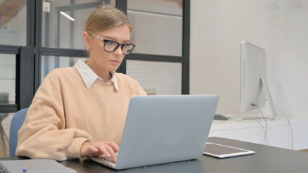 Female Worker Typing on Laptop in Officeの写真素材
