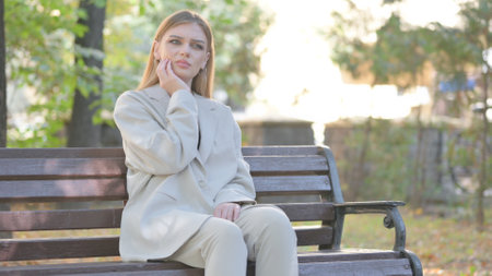 Young Business Lady with Toothache Sitting on Benchの写真素材