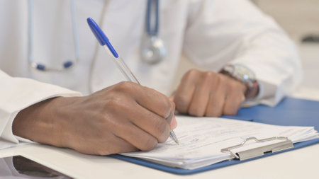 Close up of African Doctor Doing Paperwork in Hospitalの写真素材