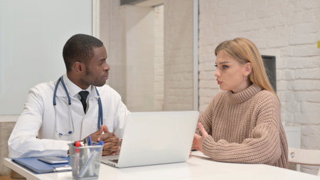 African Doctor Listening Female Patient in Clinicの写真素材