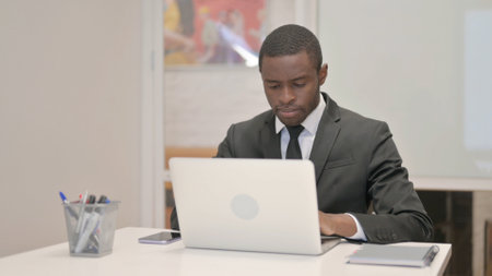 African Businessman Working on Laptop while Sitting in Officeの写真素材