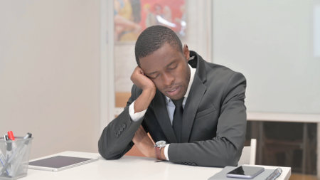 Tired African Businessman Sleeping in Officeの写真素材