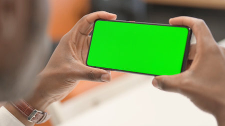 Close up of Man Holding Horizontal Smartphone with Green Screenの写真素材