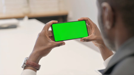 African Man Holding Horizontal Smartphone with Green Screenの写真素材
