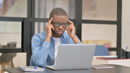 African Businessman having Headache at Workの写真素材