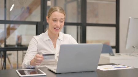Mature Business Woman Shopping Online on Laptop in Officeの写真素材