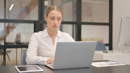 Mature Business Woman Typing on Laptop in Officeの写真素材