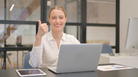 Thumbs Up by Mature Business Woman Using Laptopの写真素材