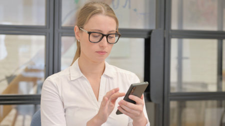 Portrait of Mature Business Woman using Phone in Officeの写真素材