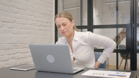 Middle Aged Business Woman with Back Pain in Officeの写真素材