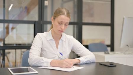 Mature Business Woman Writing a Letter in Officeの写真素材