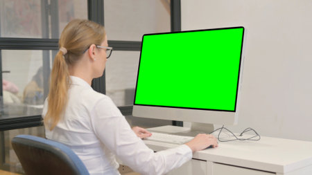 Young Woman Working on Computer with Green Screenの写真素材