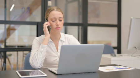 Mature Business Woman Talking on Phone at Workの写真素材