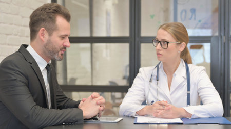 Female Doctor Listening Young Male Patientの写真素材