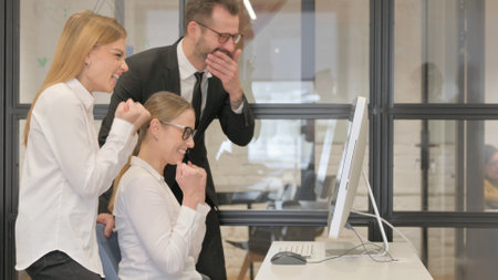 Business Colleagues Enjoying Online Success on Desktopの写真素材