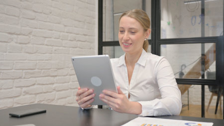 Mature Business Woman Doing Video Chat on Tablet in Officeの写真素材