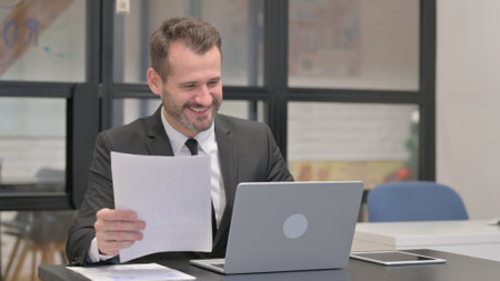 Businessman Celebrating while Doing Paperworkの写真素材