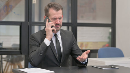 Upset Businessman in Anger Talking on Phoneの写真素材