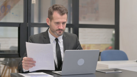 Businessman Working on Documents and Laptopの写真素材