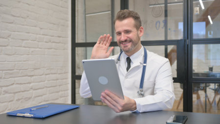 Middle Aged Doctor Doing Video Chat on Tablet in Clinicの写真素材