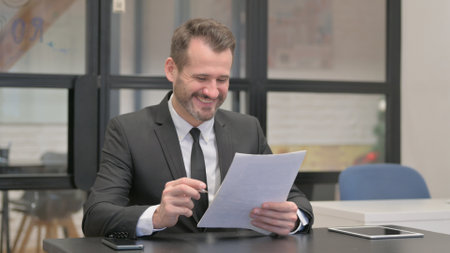 Businessman Celebrating while Reading Documentsの写真素材
