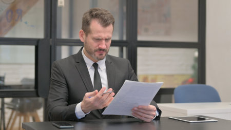 Businessman in Tension Reading Business Reportの写真素材