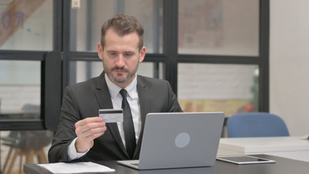 Middle Aged Businessman Enjoying Online Banking with Credit Cardの写真素材
