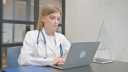 Female Doctor Typing on Laptop in Clinicの写真素材