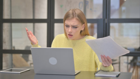 Casual Creative Woman Feeling Shocked while Working on Documents and Laptopの写真素材