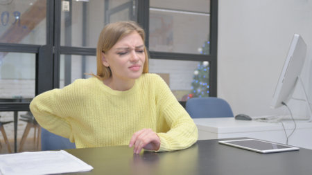 Young Blonde Woman having Back Pain while Trying to Stand upの写真素材