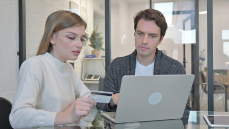 Teammates Shopping Online on Laptop in Officeの写真素材