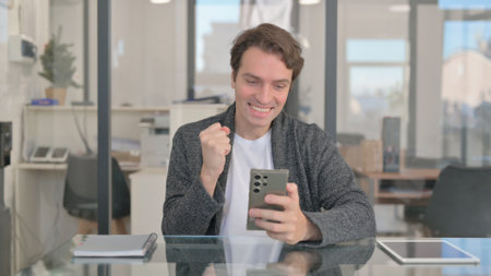 Middle Aged Man Excited for Online Trading Success on Phoneの写真素材
