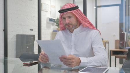 Middle Aged Muslim Man Reading Business Report at Workの写真素材