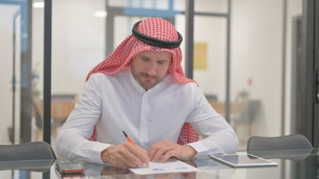 Arab Man Working on Documents in Officeの写真素材